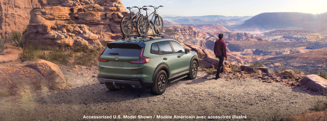 A Honda CR-V with bikes on top parked at the edge of a rocky cliff